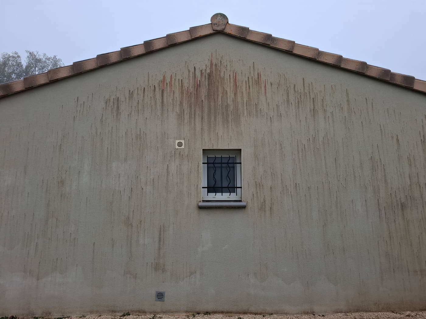 Pignon en enduit strié de coulures et de traces vertes avant nettoyage