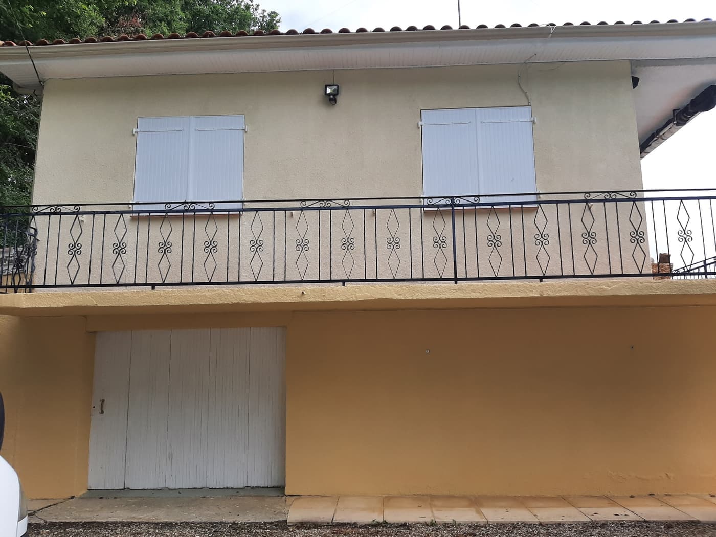 Façade de maison avant ravalement, enduit délavé et soubassement d'une teinte différente